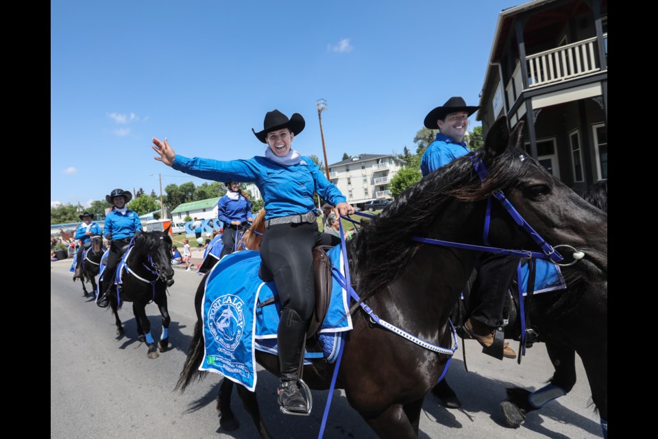 The Fort Calgary Outriders wave while riding in the 2023 Okotoks Parade on June 17.